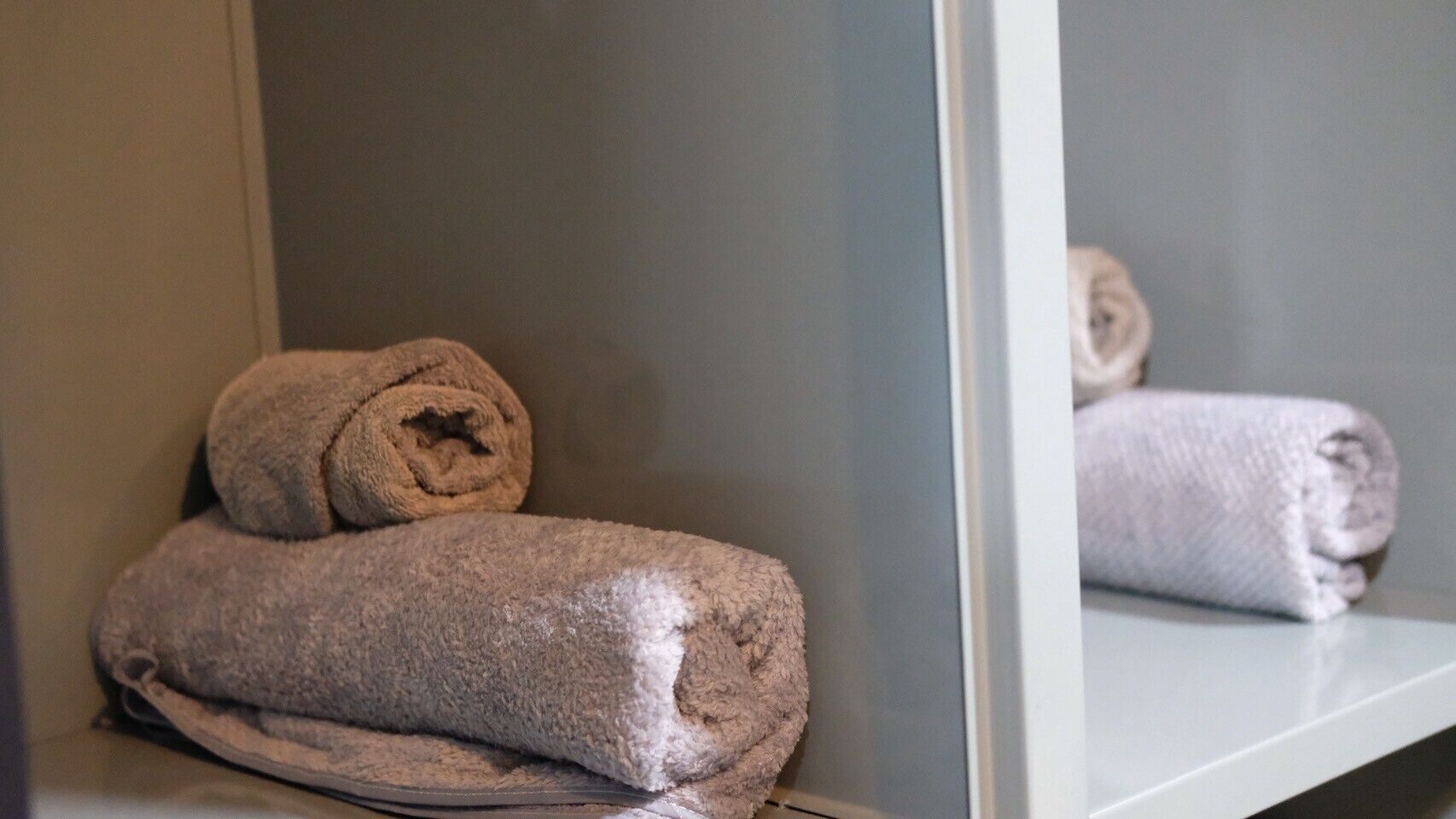 Une salle de bain avec un miroir qui reflète une serviette et un tapis de bain.