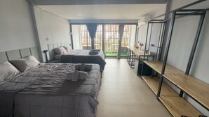 Habitación de hotel moderna con dos camas, un área de comedor y vistas al exterior.