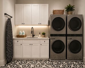 A laundry area with two stacked washing machines, a sink, and cabinets. - Luxury Retreat • Pool • Spa • Sauna • Sleeps 20+ (Tampa)