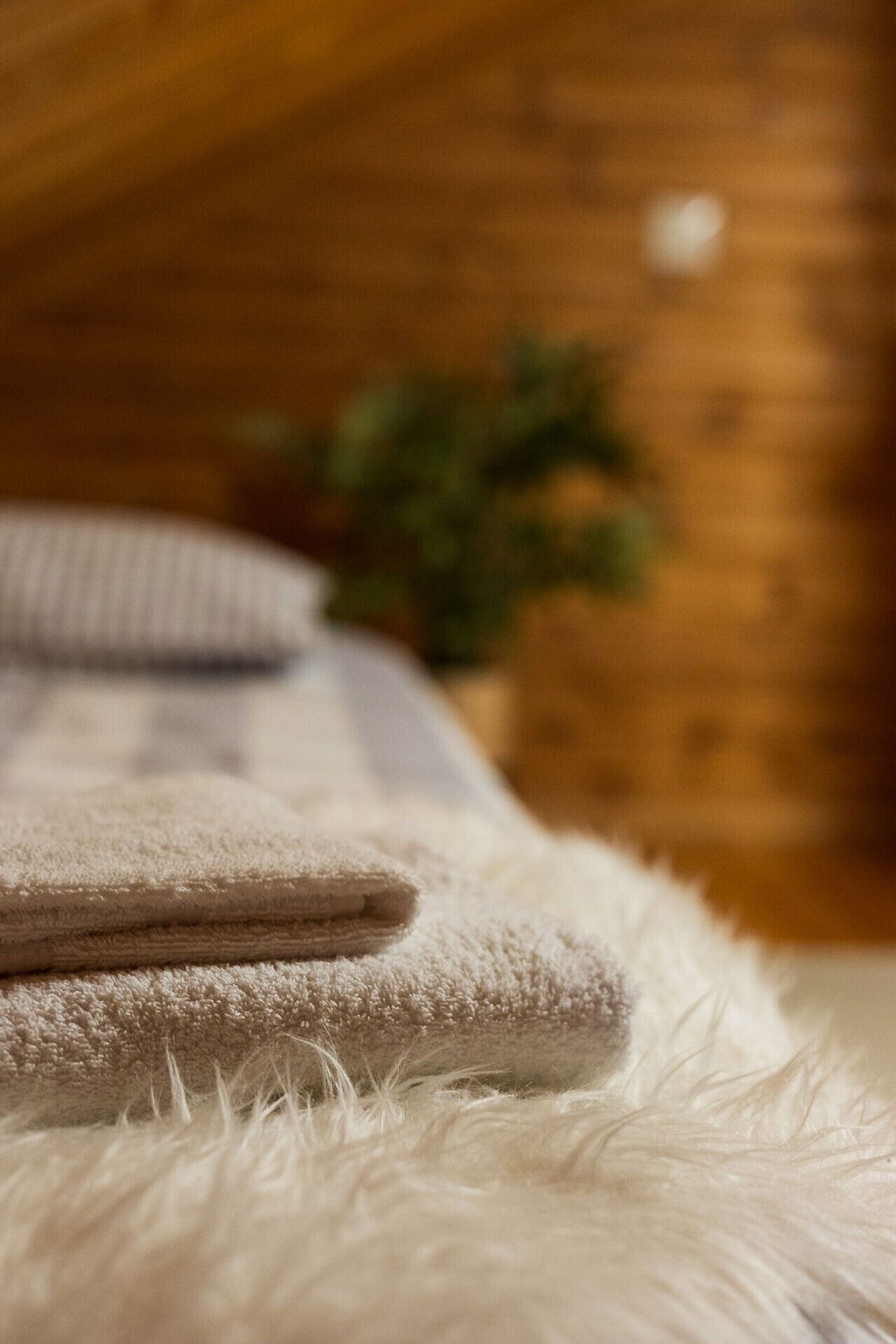 A bed with a fluffy white cover and a folded beige blanket.