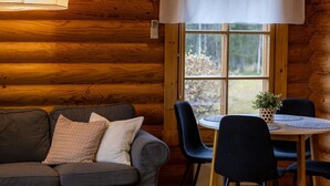 En stuga byggd av timmer med en soffa, stolar, ett bord och ett fönster med utsikt.