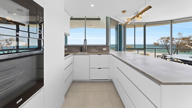 Eine moderne Küche mit Meerblick, großen Fenstern und minimalistischem Design.