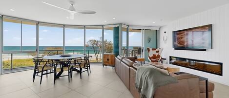 A modern living room with a large panoramic window, a ceiling fan, and a seating area with a sofa and a coffee table.