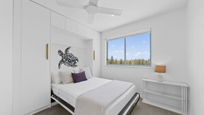 Ein Schlafzimmer mit einem Bett, einem Deckenventilator, einem Fenster mit Blick und einem Nachttisch mit Lampe.
