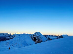 A snow-covered mountain landscape with a ski lift and a person skiing.