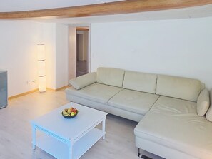 Un salon avec un canapé, une table basse sur laquelle se trouvent des fruits et un téléviseur.