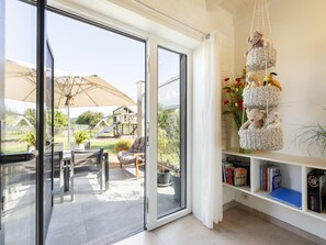 Ein modernes Interieur mit einer Schiebetür zu einer Terrasse, einem Bücherregal mit Büchern und einer Hängekorb mit Stofftieren.