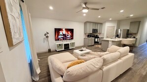 Ein modernes Wohnzimmer mit einem weißen Sofa, einem Flachbildfernseher und einem Deckenventilator.