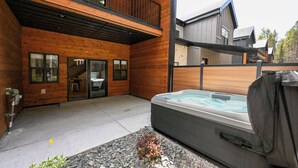 Un edificio moderno in legno con una vasca idromassaggio e un'area barbecue coperta.