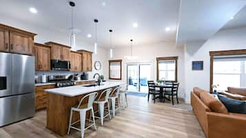 A modern kitchen with stainless steel appliances, wooden cabinets, and a central island with bar stools.