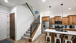 Una cucina moderna con mobili in legno, elettrodomestici in acciaio inossidabile e un'isola centrale con sgabelli da bar.