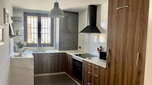 A modern kitchen with dark wood cabinets, a black range hood, and a white pendant light.