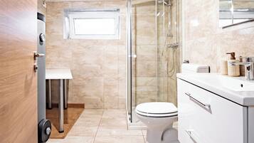Un bagno moderno con un water, una doccia e un mobile lavabo.