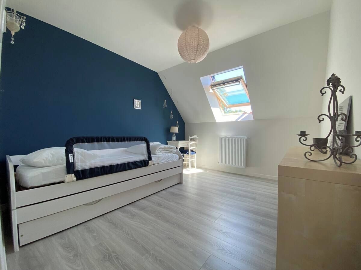 Un dormitorio con cama, escritorio, radiador y vistas al exterior.