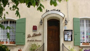 Entrada de un hotel con puerta de madera, contraventanas verdes y un letrero que dice 'Le Pêche Hotel de Charme'.