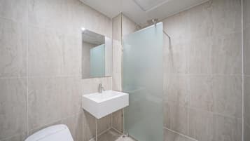 Un baño con un lavamanos blanco, un espejo y una cabina de ducha de vidrio.