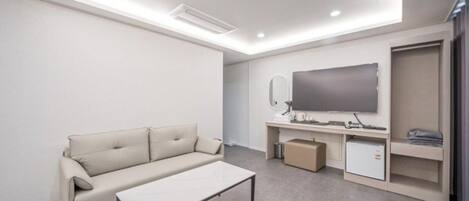Una sala de estar moderna con un sofá, una mesa de centro, un televisor de pantalla plana, un espejo y armarios de almacenamiento.