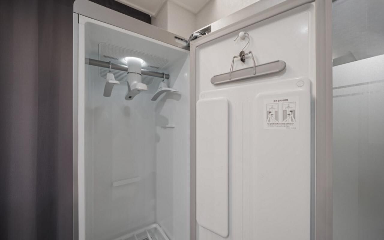 A modern bathroom with a glass partition, a towel rack, and a hand sanitizer dispenser.