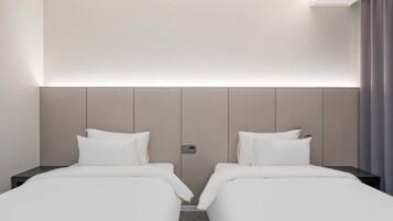A hotel room with two beds, a headboard, a control panel, and a curtain.