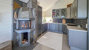 Une cuisine moderne avec une cheminée en pierre, des meubles gris et un tapis blanc.