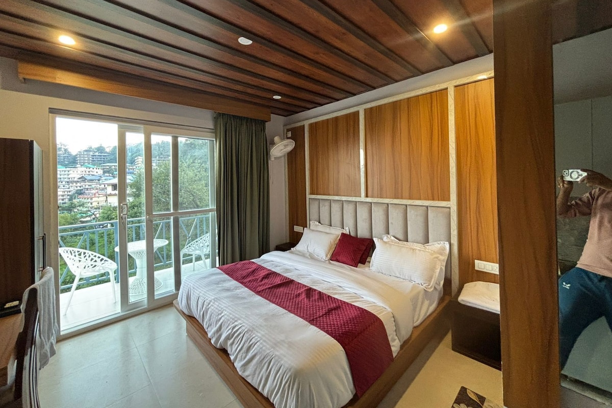 Une chambre avec un grand lit, une vue sur l’extérieur grâce à une porte coulissante donnant sur un espace extérieur, et un plafond en bois.