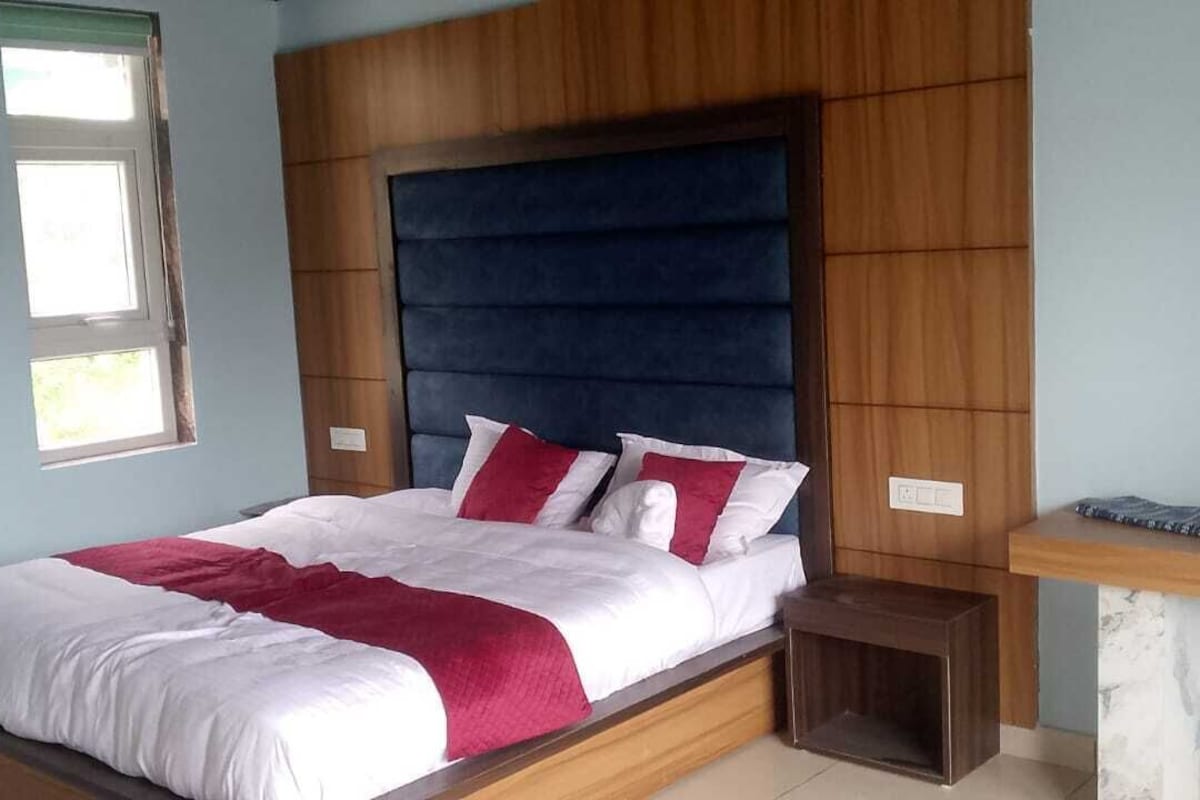 Une chambre à coucher avec un lit, une table de chevet, une fenêtre et une tête de lit en bois.