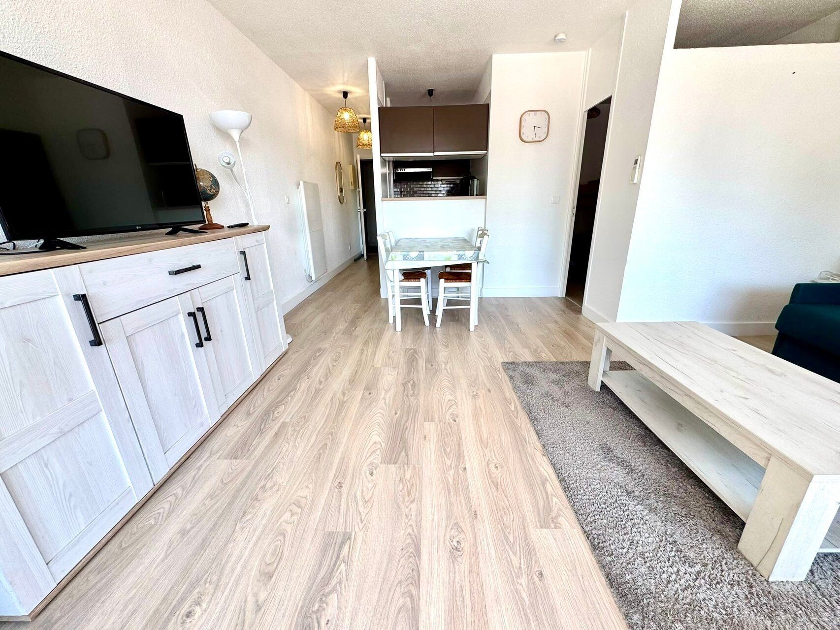 Een moderne keuken met witte kasten, een eettafel en een bankje.