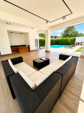 Uma sala de estar moderna com um sofá modular, uma mesa de centro e vista para uma piscina.