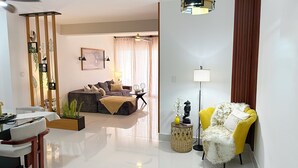 A modern living room with a sofa, a yellow chair, a dining table, and a floor lamp. - Boho Luxury Stay•Pool•Gym/Near Everything (Santiago de los Caballeros)