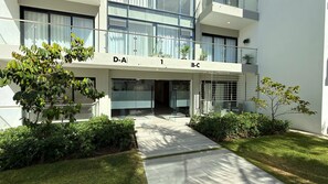 Um edifício moderno com fachada de vidro, com números de quarto indicados como D-A e B-C, e uma entrada coberta.