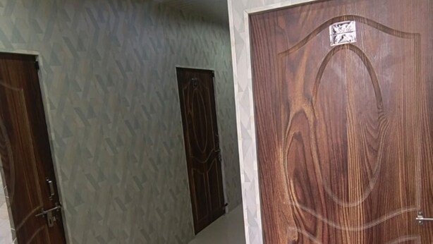 A hallway with patterned walls, wooden doors, and a tiled floor.