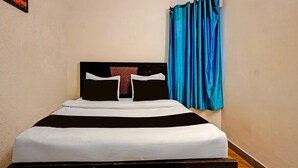 A single bed with a black and white headboard, a blue curtain, and a framed picture on the wall. - Deluxe Hotel Shhalom (Haldwani)