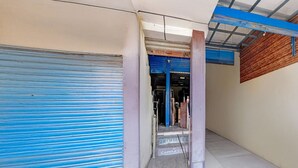 A corridor with closed blue shutters, a concrete floor, and a wooden wall. - Deluxe Hotel Shhalom (Haldwani)