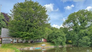 A lakeside property with a dock, a small building, and a large tree. - Cozy home in Føvling with WiFi (Føvling)
