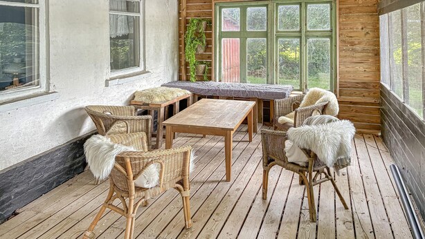 A wooden deck with wicker furniture, a checkered table, and a green door. - Cozy home in Føvling with WiFi (Føvling)