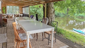 A covered outdoor dining area with a table and chairs, overlooking a body of water. - Cozy home in Føvling with WiFi (Føvling)