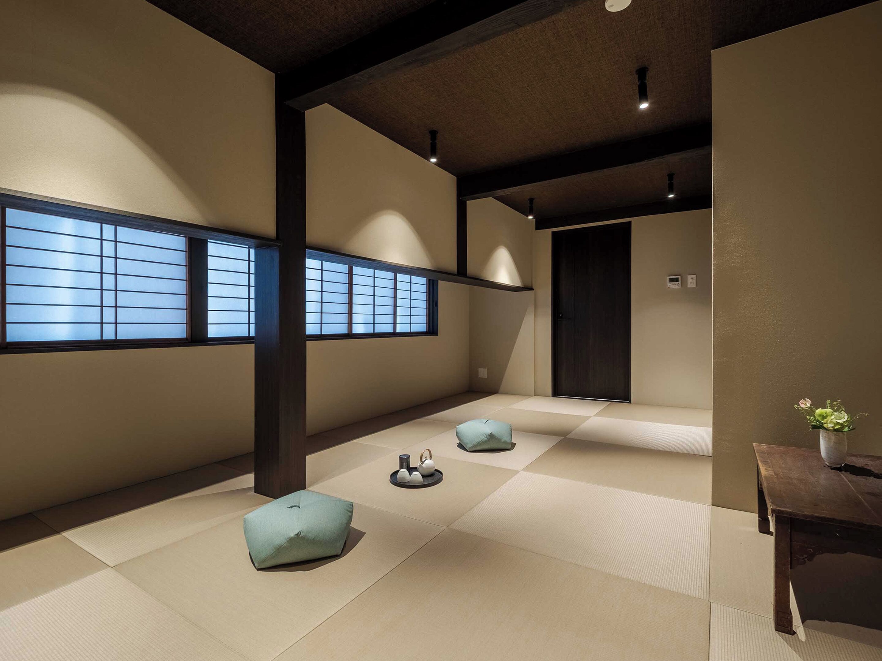 Una tradizionale stanza giapponese con pavimento in tatami, porte scorrevoli e un piccolo tavolo con un vaso.