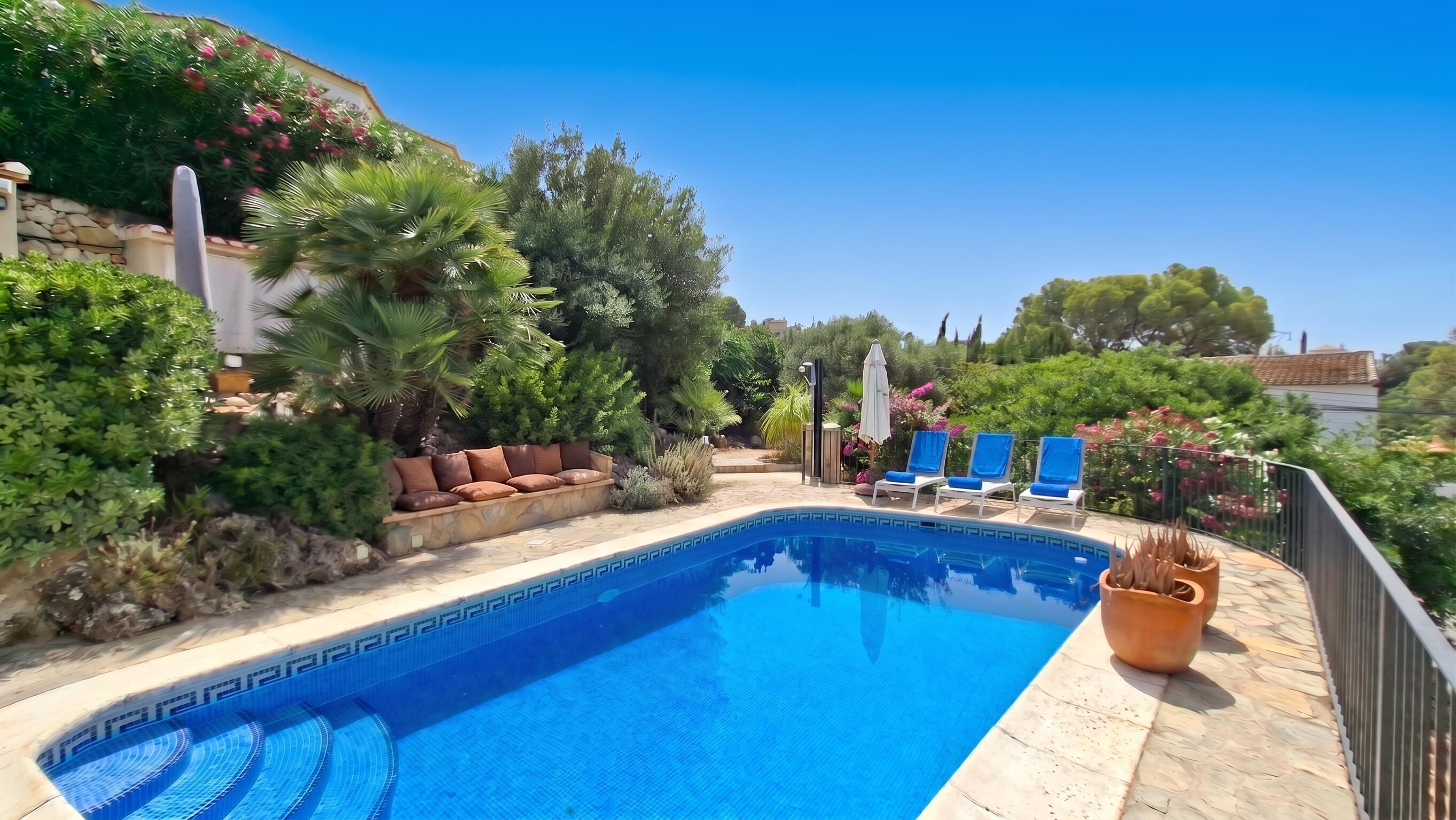 A swimming pool with lounge chairs and a stone wall.