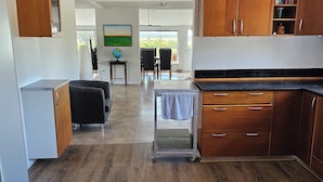 Une cuisine moderne avec des meubles en bois, un coin repas comprenant une table et des chaises, et une vue à travers une porte vitrée.
