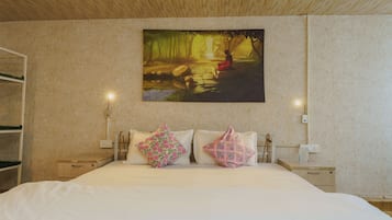 Quarto com uma cama, duas mesas de cabeceira, um criado-mudo, um quadro na parede e teto de madeira.