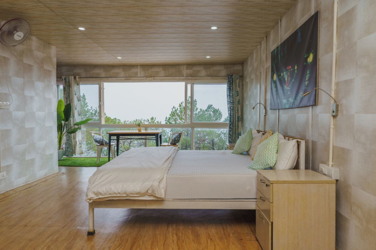 Un dormitorio con cama, mesita de noche y vistas al exterior.