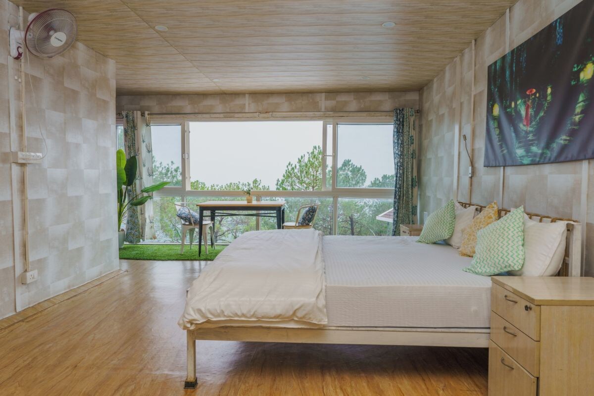 Un dormitorio con cama, mesita de noche y ventana con vistas a zonas verdes.