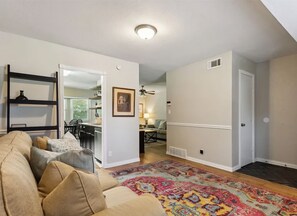 A living room with a sofa, a colorful rug, and a kitchen in the background. - Peaceful 4-bdrm HomeAway Texas Rose Euless with covered patio and fenced yard. (Euless)