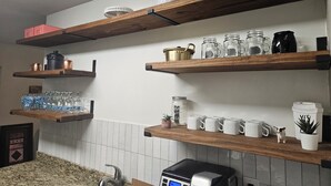 Una cocina con estantes de madera que exhiben diferentes utensilios, una cafetera y una pequeña planta.