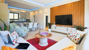 A modern living room with a sofa, a coffee table, and a TV mounted on a wooden wall. - Villa Fonte, outstanding view, large pool (İslamlar)