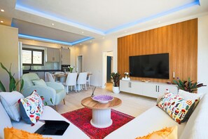 A modern living room with a sofa, a coffee table, and a TV mounted on a wooden wall. - Villa Fonte, outstanding view, large pool (İslamlar)