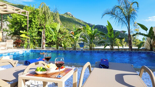 A poolside setting with lounge chairs, a table with a glass of red wine, and a view of a mountain. - Villa Fonte, outstanding view, large pool (İslamlar)