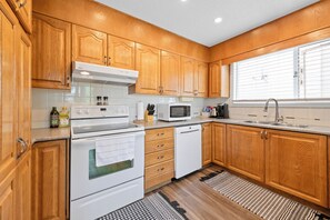 Une cuisine moderne avec des meubles en bois, une cuisinière, un four à micro-ondes et un lave-vaisselle.