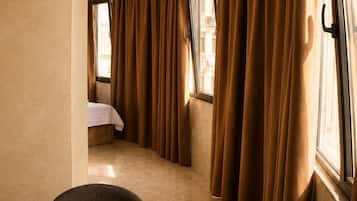Una habitación de hotel con una mesa redonda de mármol, dos sillas y una cama al fondo.