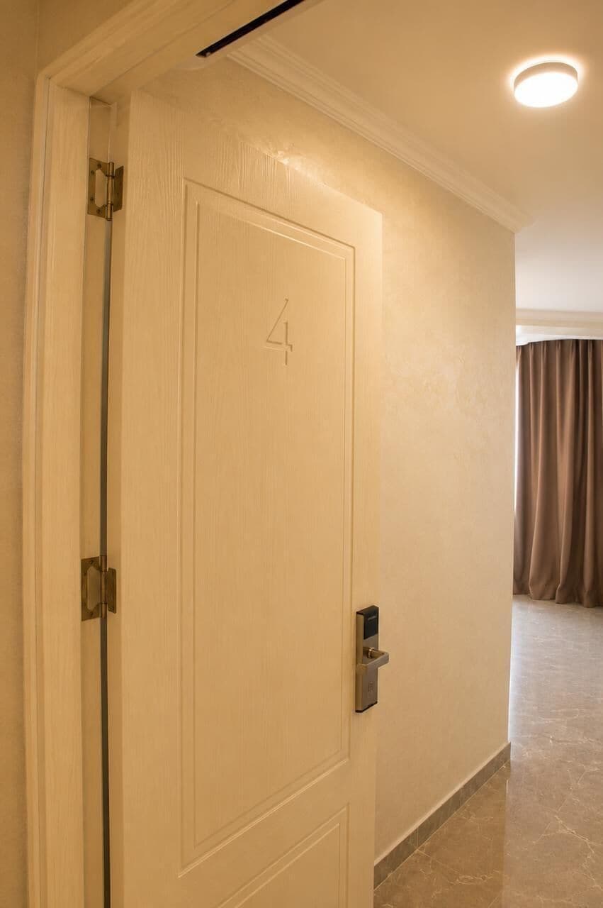 Puerta de habitación de hotel con el número 4, un picaporte y una cerradura.